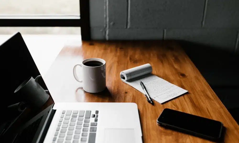 ordinateur avec une tasse de café et un bloc notes