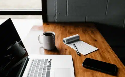 ordinateur avec une tasse de café et un bloc notes