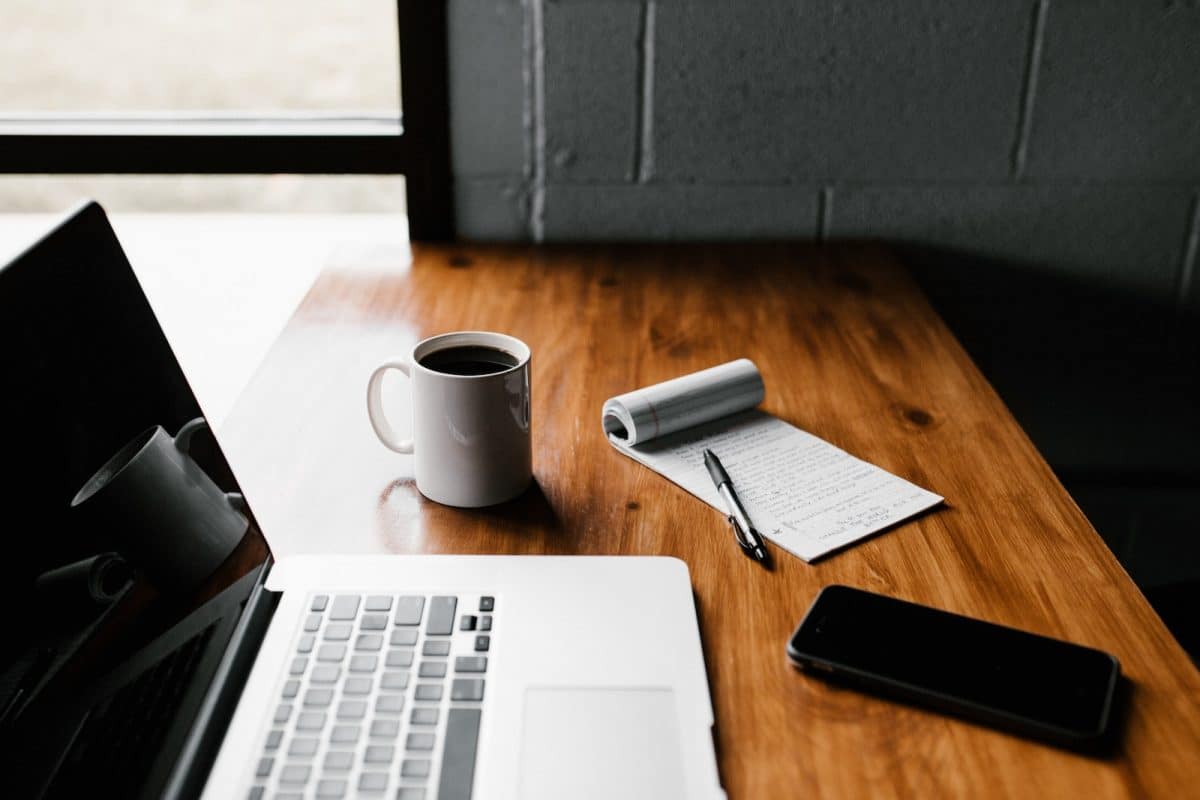 ordinateur avec une tasse de café et un bloc notes